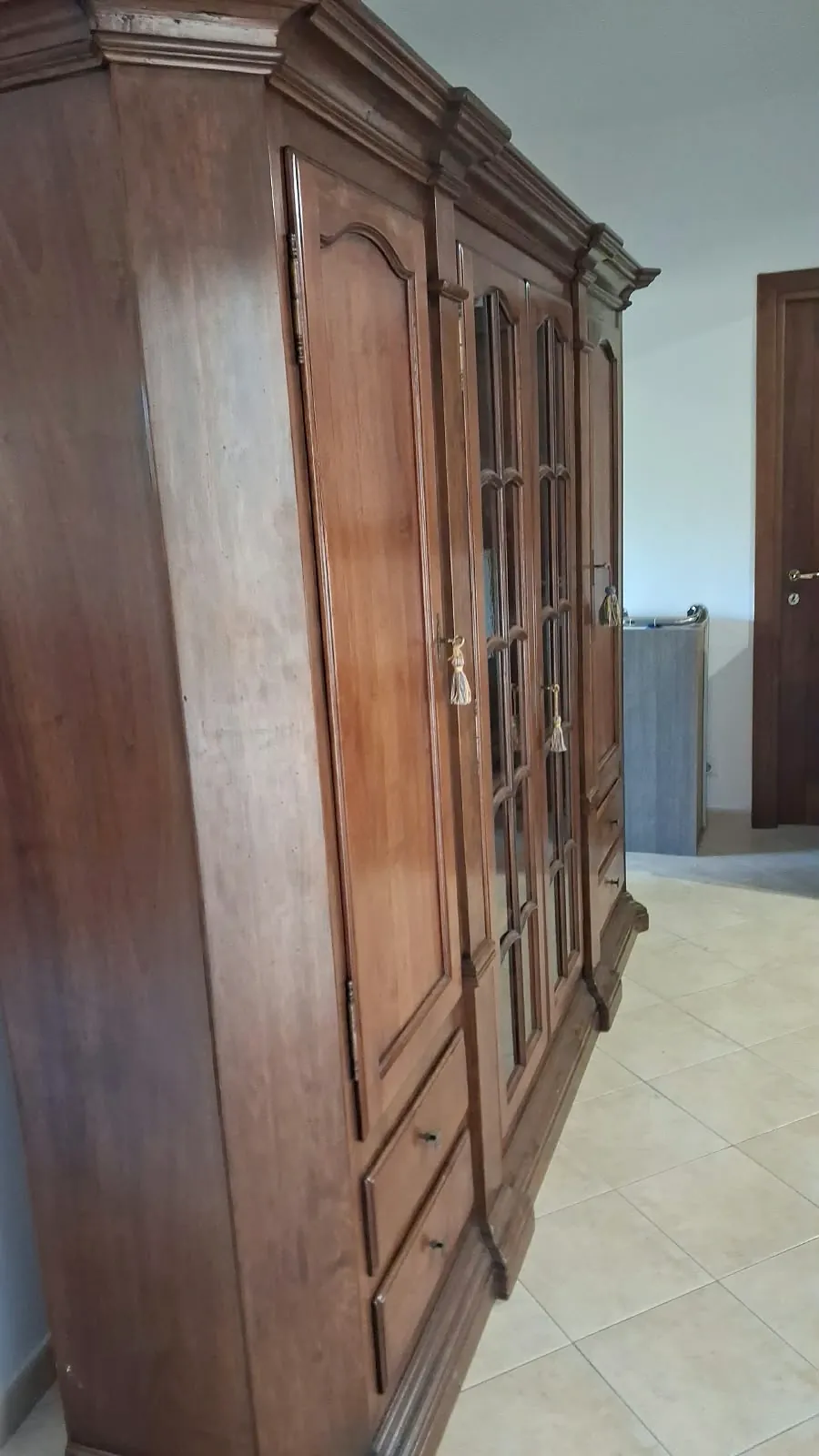 Armadio classico in legno scuro con due ante a vetri e i cassetti