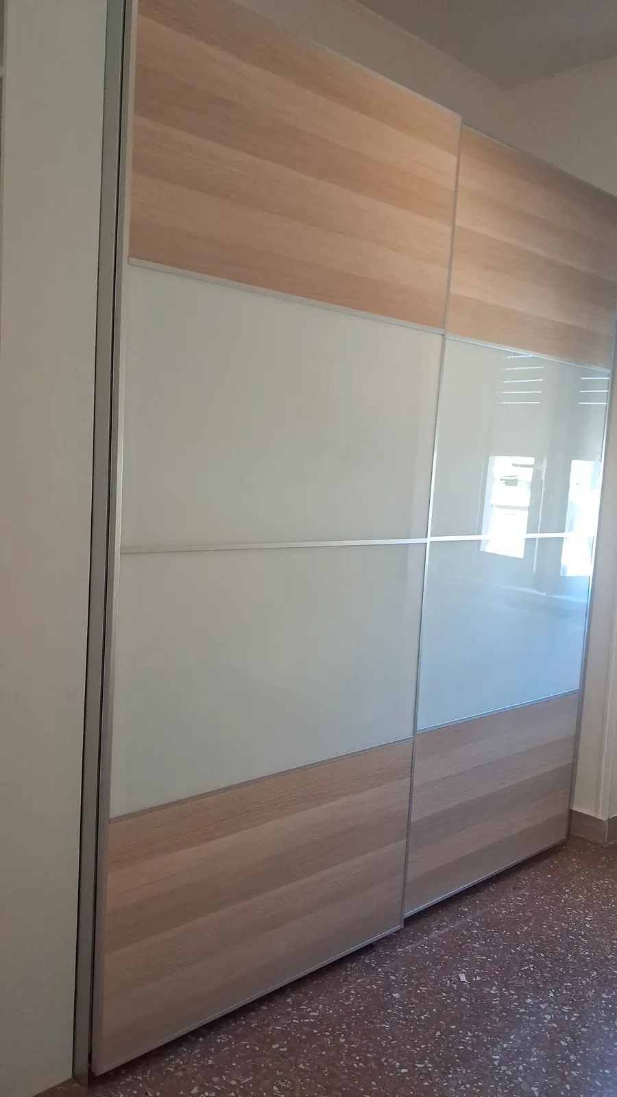 Armadio con due ante scorrevoli in legno chiaro e vetro bianco, montato