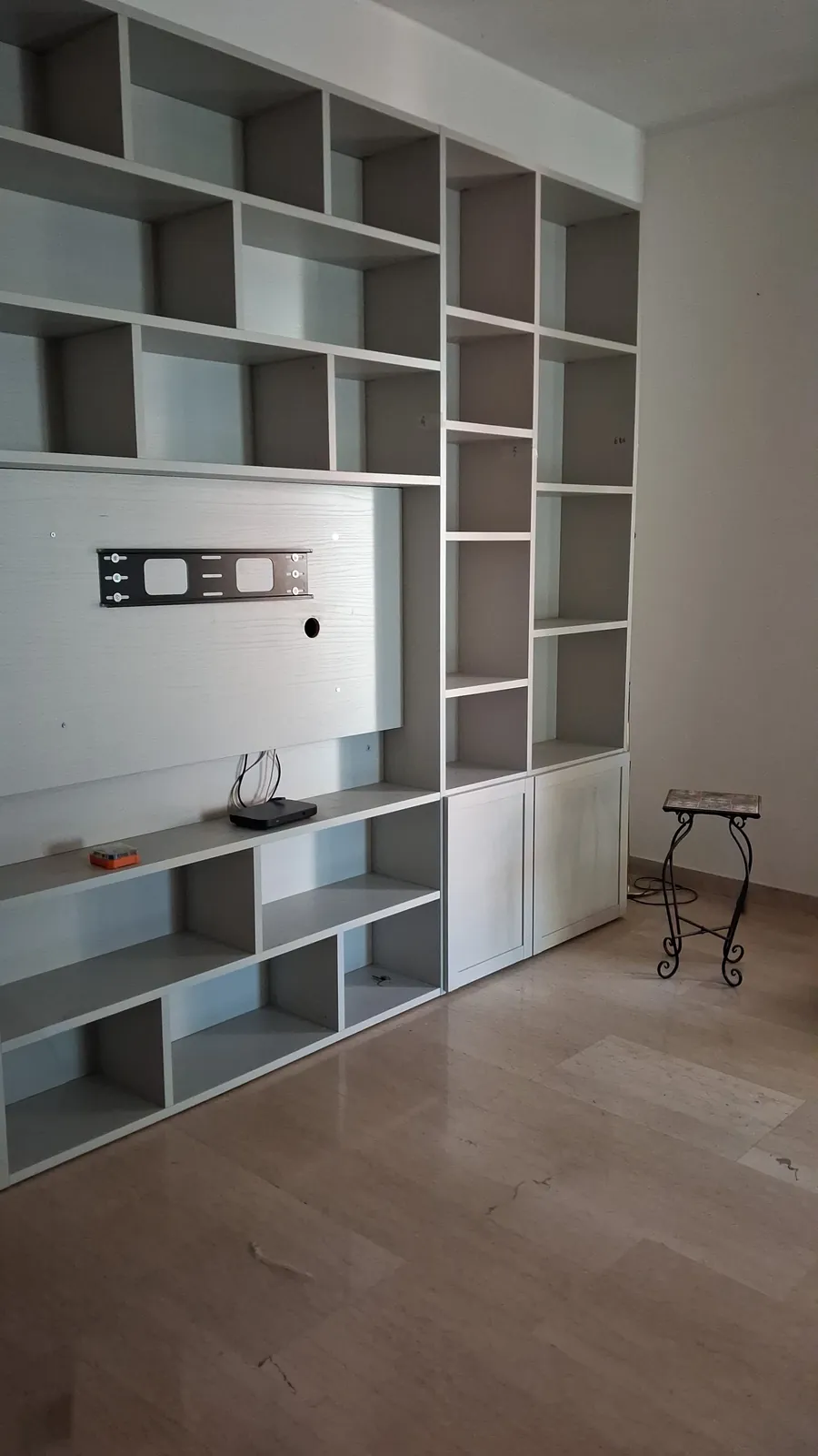 Libreria grigia a muro con il pannello per il televisore, montata nel soggiorno